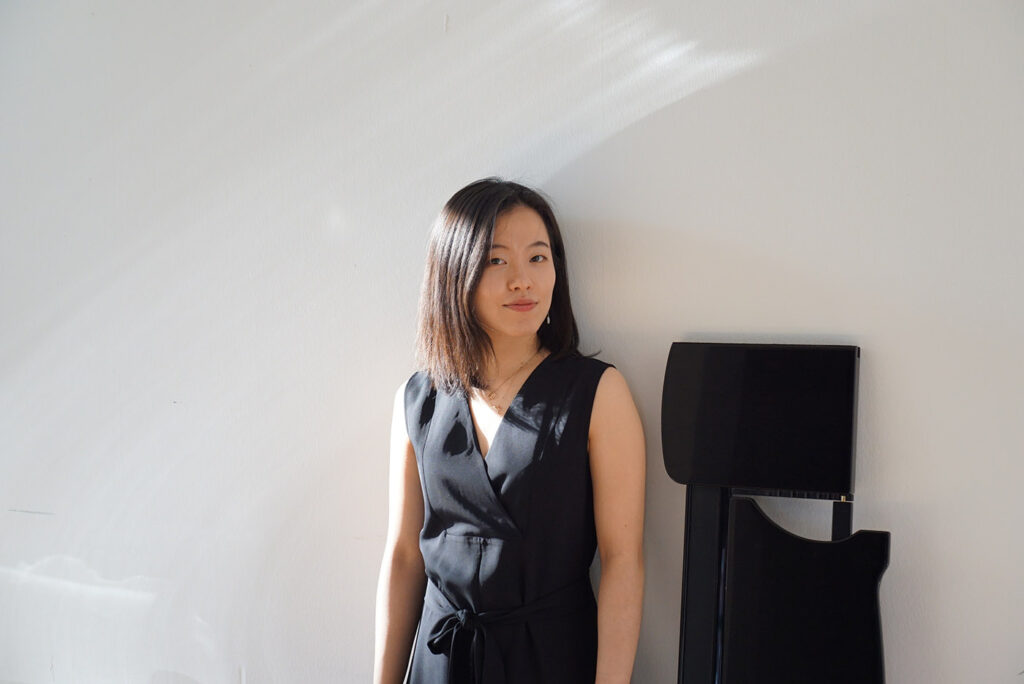 Nainen mustassa mekossa valkoisen seinän edessä