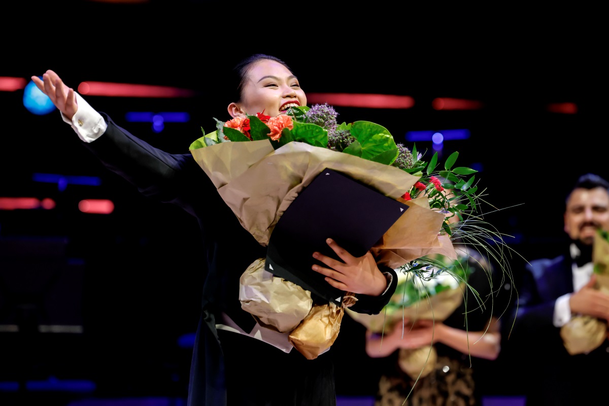 Jingjing Xu on stage with bouquet.