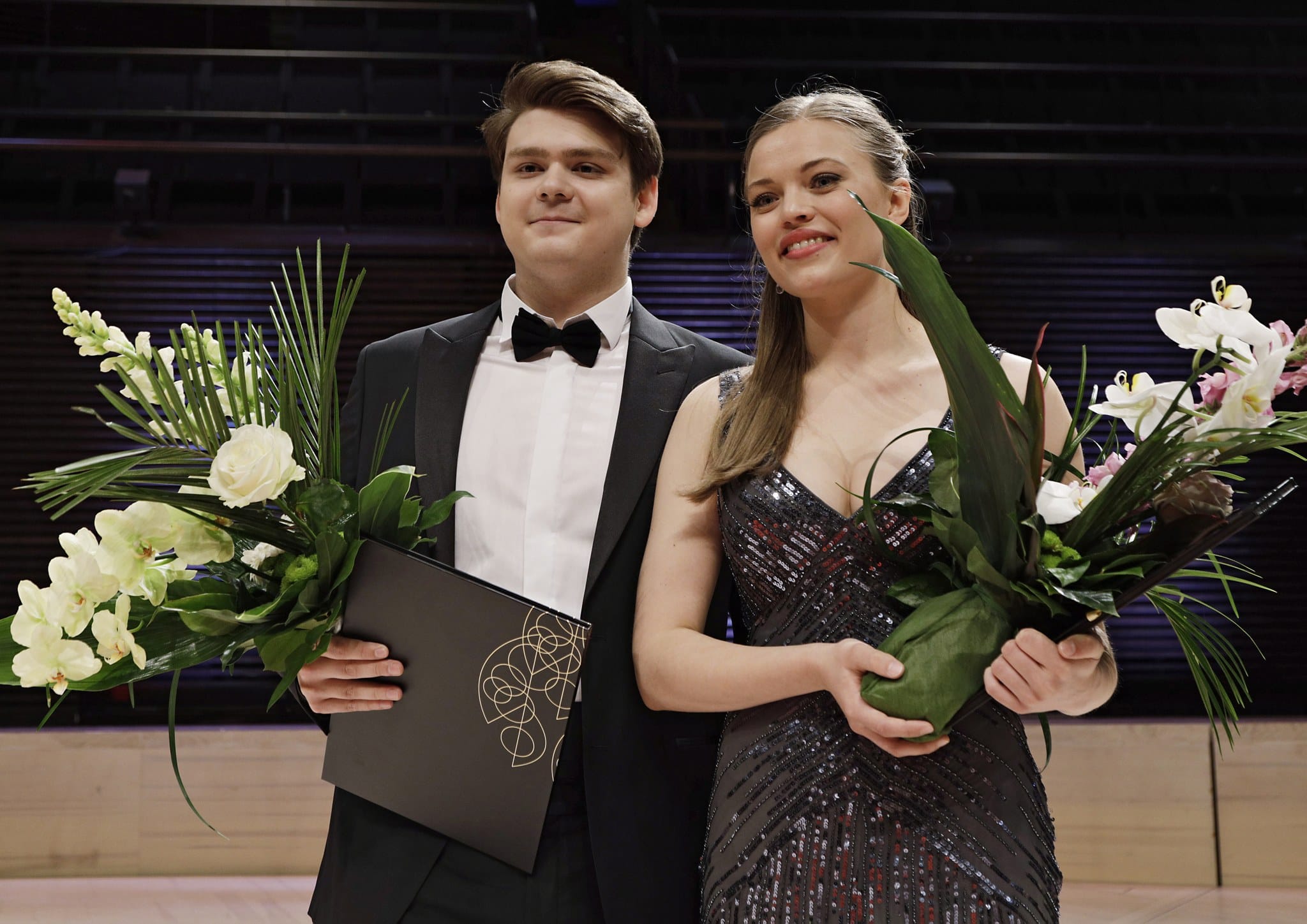 Stefan Astakhov and Johanna Wallroth on Musiikkitalo stage with flower bouquets.